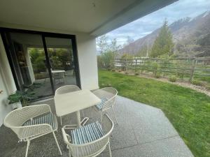 een tafel en stoelen op een patio met uitzicht op een berg bij Garden Apartment in Queenstown