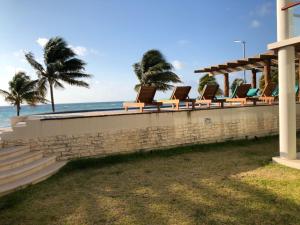 uma fila de cadeiras sentadas numa parede junto ao oceano em Casa Diany em Mahahual