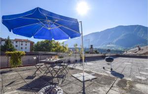 ein blauer Regenschirm auf einer Terrasse mit einem Tisch und Stühlen in der Unterkunft Beautiful Apartment In Feltre With Kitchen in Feltre
