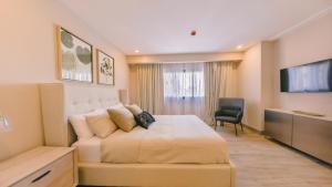 een slaapkamer met een bed, een bank en een televisie bij Fully Serviced Apartment at Regatta Living II - 905 in Santo Domingo