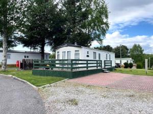 a mobile home with a green fence in front of a house at 'Oakley' Boat of Garten Holiday Park in Boat of Garten