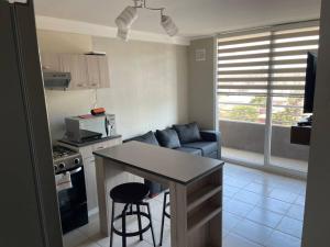 a kitchen and living room with a table and a couch at Hermoso Depto Piscina Quincho in Rancagua