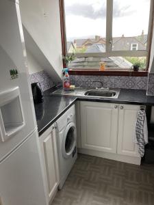 a kitchen with a sink and a washing machine at 2 Bedroom apartment, with free parking in Largs