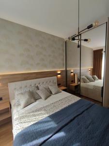 a bedroom with a large white bed and a mirror at GRAND LUX APARTMENTS in Banja Luka