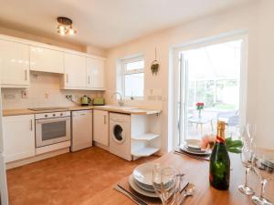 a kitchen with white cabinets and a table with wine glasses at Wisteria Place in Tiptree