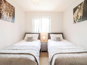 two beds in a room with white walls at Wisteria Place in Tiptree