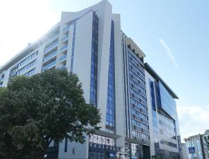 un edificio blanco alto con un árbol delante de él en GRAND LUX APARTMENTS en Banja Luka