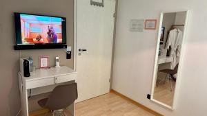 um quarto com uma televisão, uma secretária e um espelho em smart&beautiful Guesthouse em Nordkirchen