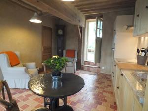 a kitchen with a table and a living room at Gîte de charme Floréales Les Iris in Asnelles