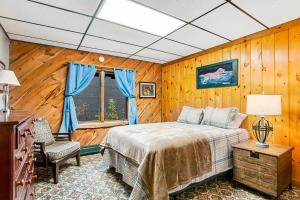 1 dormitorio con paredes de madera, 1 cama y ventana en The Bear Lodge, en Winchester