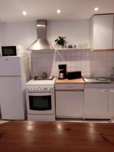 kuchnia z białą kuchenką i lodówką w obiekcie petite maison chaleureuse w mieście Irvillac