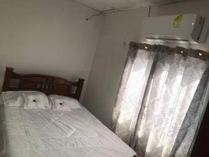 um quarto com uma cama com lençóis brancos e uma janela em Donde Bris em Ríohacha