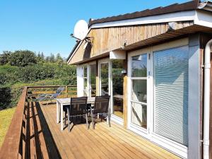 eine Holzterrasse mit einem Tisch und Stühlen darauf in der Unterkunft Seaside Serenity at Hvidbjerg-By Traum in Børkop