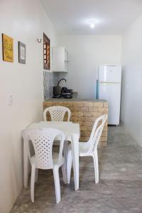 Una mesa blanca y sillas en una cocina con nevera. en Chalés Solmar, en Itapipoca