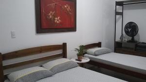 a bedroom with two beds and a potted plant at APARTAMENTO PRÓXIMO A PRAIA PISCINA E AREA GOURMET in Ubatuba
