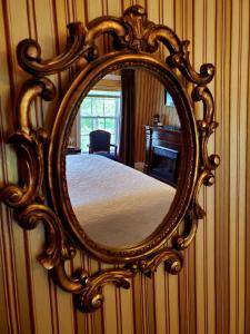 a mirror on a wall with a bed in a room at Darlington House Bed and Breakfast in Niagara on the Lake