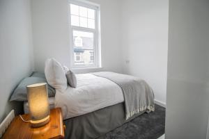 a white bedroom with a bed and a window at Dwellcome Home Ltd 2 DOUBLE Bedroom 3 Bed Apt, Fast WIFI, Free Street Parking, Ideal for Long Term Contractor, etc Stays, Regular Housekeeping Option, 10 min Walk from Beach and Metro 15-20 min Drive to Nissan & Newcastle - See our Site for Assurance in South Shields