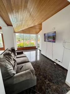 a living room with a couch and a flat screen tv at Finca tres colinas in Lemos