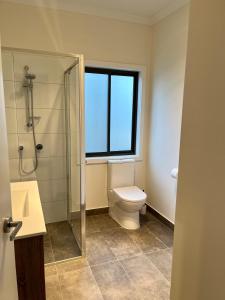 a bathroom with a toilet and a glass shower at High Country Holiday Park in Mansfield