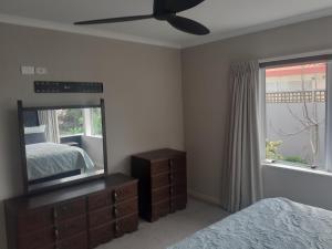 ein Schlafzimmer mit einem Spiegel, einem Bett und einer Kommode in der Unterkunft Pavilion Beachfront Apartments in Mount Maunganui
