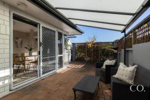 a patio with awning and chairs and a table at Pavilion Beachfront Apartments in Mount Maunganui