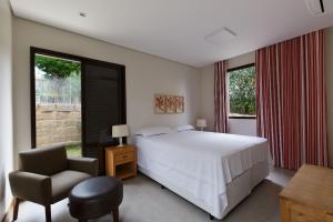 1 dormitorio con 1 cama, 1 silla y ventanas en Mansão luxuosa com área de lazer em Valinhos, en Valinhos