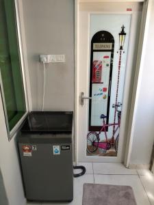 a small refrigerator in a hallway with a bike in the doorway at JOE Homestay in Alor Setar