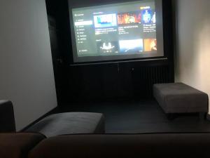 a room with a large screen with a couch and a stool at Paradis Du Nord in Wallers