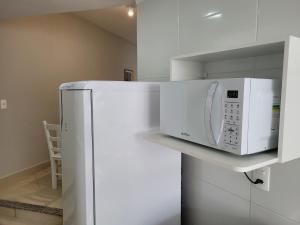eine Küche mit einem weißen Kühlschrank und einer Mikrowelle in der Unterkunft Apartamento completo no centro de Tijucas 105 in Tijucas