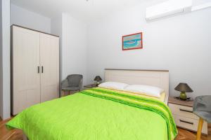 a bedroom with a bed with a green blanket on it at Double Room Pasman 4309d in Pašman