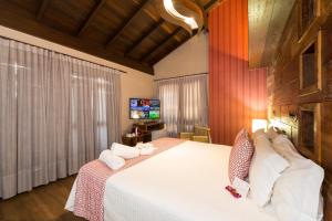 1 dormitorio con 1 cama blanca grande y TV en Hospedaria Refúgio das Galés en Bombinhas