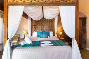 1 dormitorio con cama con dosel y almohadas azules en Hospedaria Refúgio das Galés, en Bombinhas