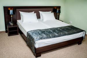 ein großes Bett in einem Hotelzimmer mit zwei Lampen in der Unterkunft Churchill-Inn in Winnyzja