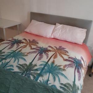 a bed with a blanket with palm trees on it at 2-bedroom Back Hilton Area apartment - Ground Floor, Aberdeen city center in Aberdeen