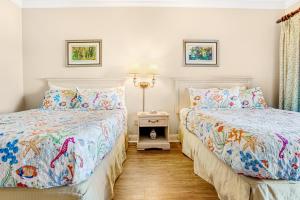 two beds in a room with white walls at 256 Sandcastles - Hotel Side in Fernandina Beach