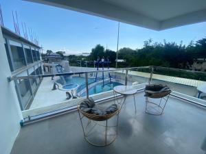 a balcony with a swimming pool and two chairs and a table at J&V Hotel and Resort in Apaleng