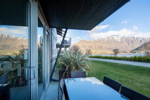 a porch with a table and chairs and mountains at Marina Apartments - Element Escapes in Queenstown