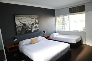 una habitación con 2 camas y una foto de un toro en Motel Melrose, en Mittagong