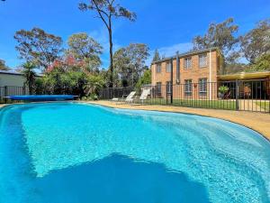 a large blue swimming pool in front of a house at Tallowood House in Nulkaba