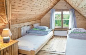 two beds in a wooden room with a window at 4 Bedroom Stunning Home In Milakowo in Miłakowo