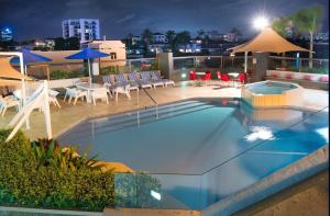 una piscina con sillas y sombrillas en un edificio en Tiki Hotel Apartments Surfers Paradise en Gold Coast