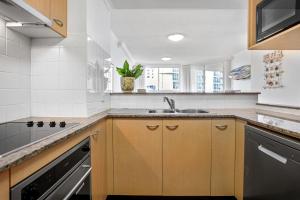 a kitchen with a stove top oven and a sink at Kirra Beach Apartments in Gold Coast