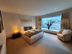 a bedroom with a bed and a chair and a window at Luxury Home with Beautiful Lake & Mountain Views in Queenstown