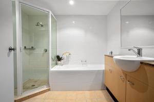 a bathroom with a tub, sink and mirror at Kirra Beach Apartments in Gold Coast