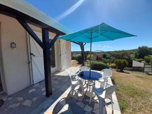 eine Terrasse mit einem Tisch, Stühlen und einem blauen Sonnenschirm in der Unterkunft Maison avec jardin près des Thermes, 2 chambres, équipements modernes, à La Roche-Posay - FR-1-541-33 in La Roche-Posay
