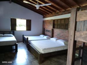 1 Schlafzimmer mit 2 Betten und Ziegelwand in der Unterkunft Hostal finca Palermo in Santa Fe de Antioquia