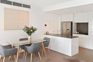 Una cocina y un comedor con mesa y sillas. en Luxury Overlooking Hindmarsh Sq with Pool & Gym, en Adelaida