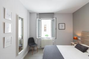 a white bedroom with a bed and two windows at Apartamento Foro Romano in Zaragoza