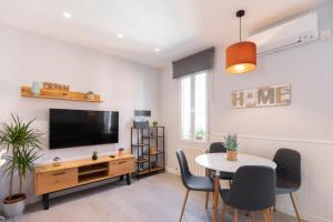 sala de estar con TV, mesa y sillas en Apartamento Foro Romano en Zaragoza