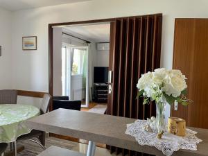 a living room with a table with a vase of flowers at Apartments Veli Rat in Veli Rat